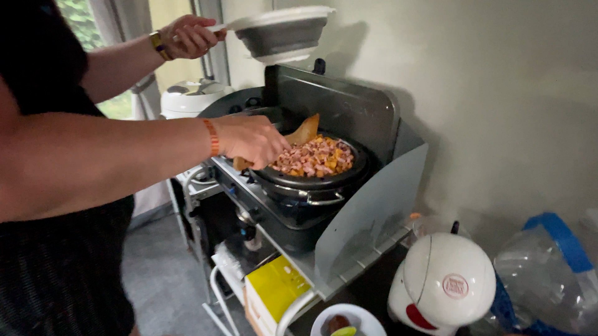 Préparation d'un repas sur le réchaud d'un camping-car, avec passoire pliable et petit électroménager à bord